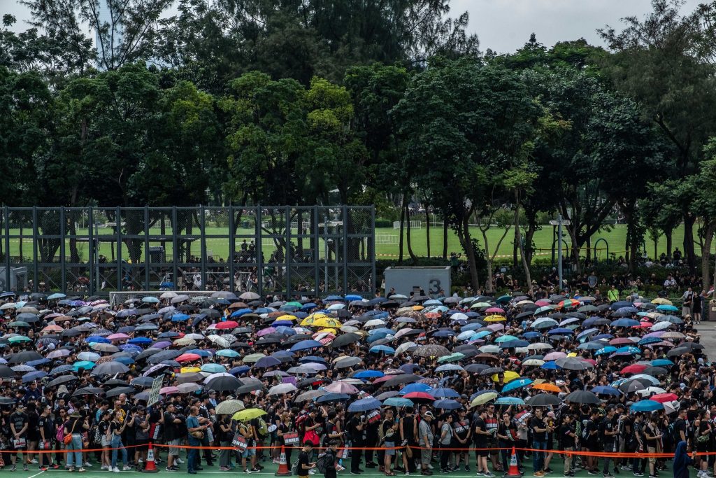 Marchers wait in Victoria Park with umbrellas