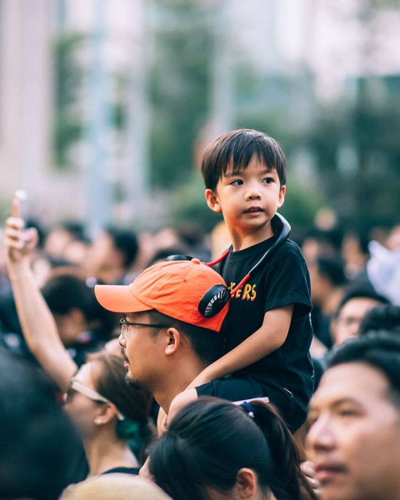 Child on his father's shoulders overlooking the protest